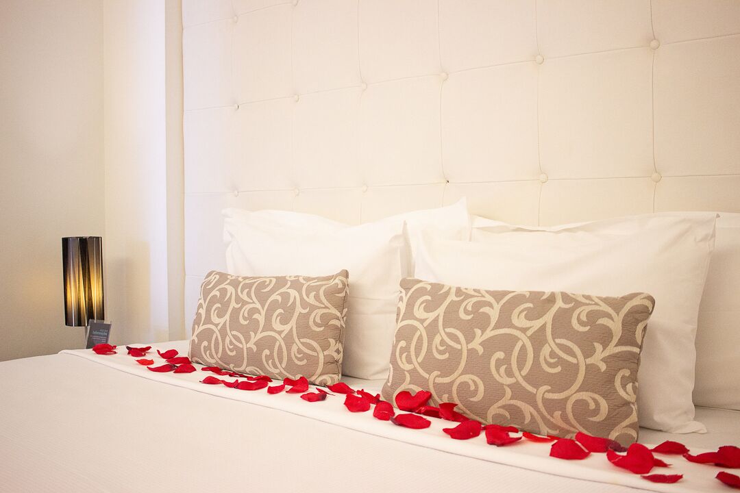 A hotel room with a tufted headboard, white bedding, and decorative pillows.