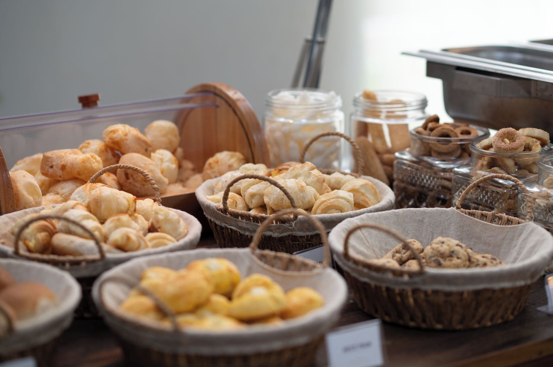 A display of various baked goods including bread, pastries, and cookies in baskets and jars.