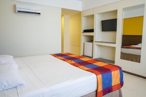 Una habitación de hotel con cama, televisor, armario y una pequeña kitchenette.
