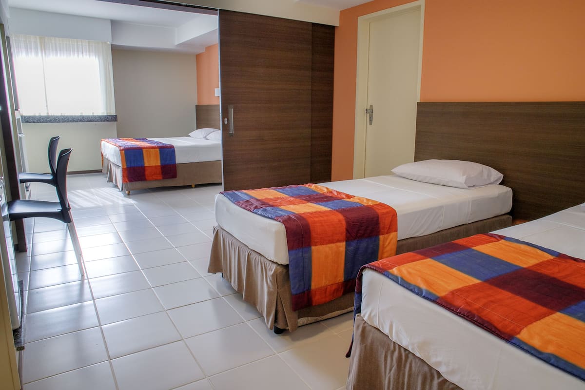A hotel room with two beds, a desk, and a chair.