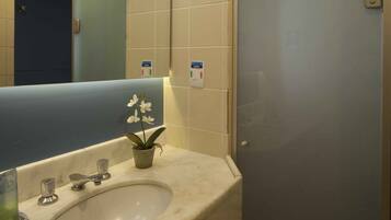 A bathroom with a sink, mirror, and a glass shower enclosure.