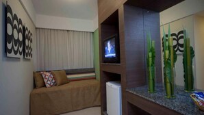 A modern living room with a sofa, a television, and decorative glass vases. - Park Hotel (Recife)