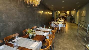 Un restaurante con varias mesas, sillas y una lámpara colgante original.