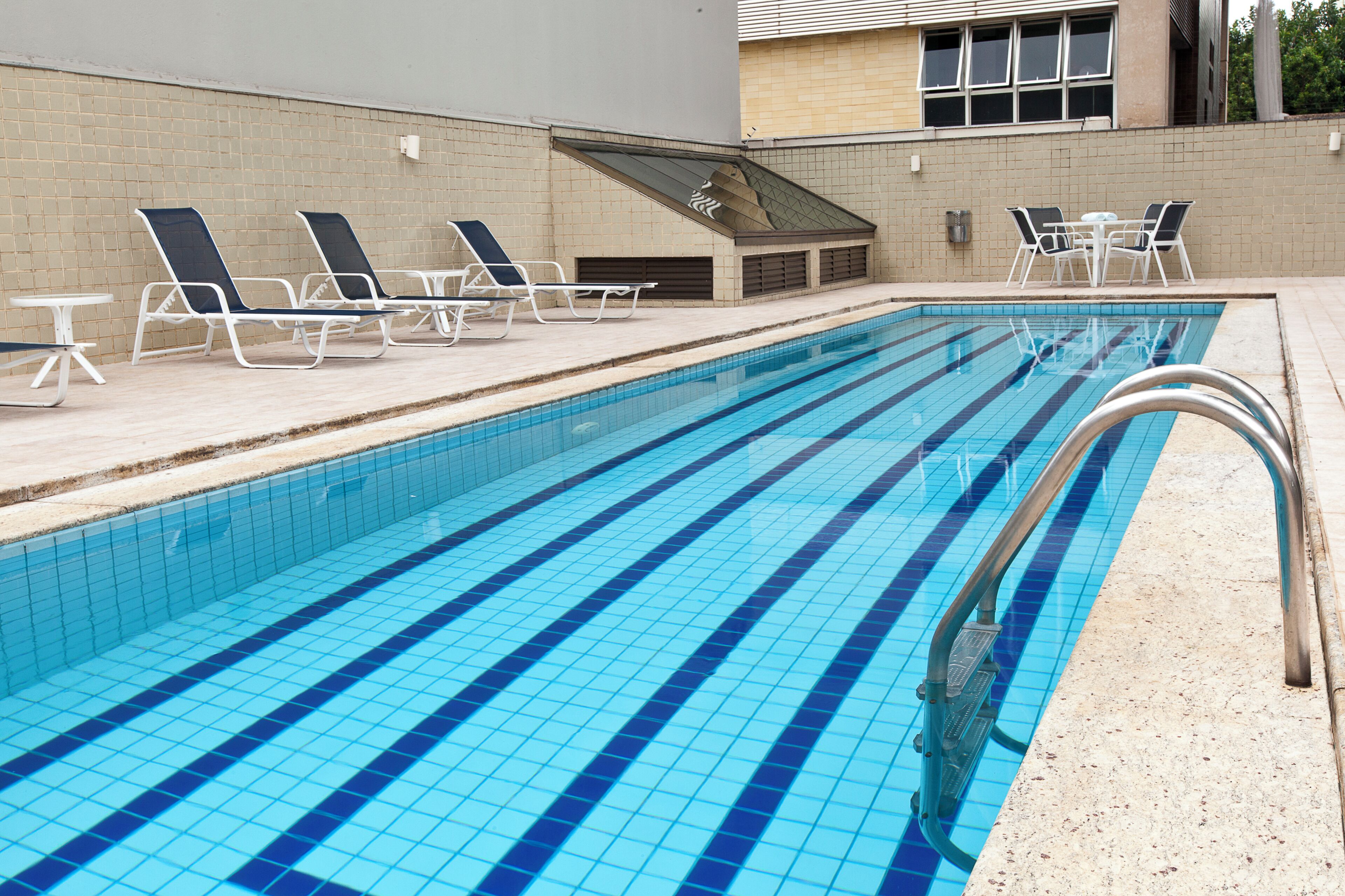 Una piscina al aire libre, sillones reclinables de piscina