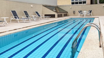 Una piscina al aire libre, sillones reclinables de piscina