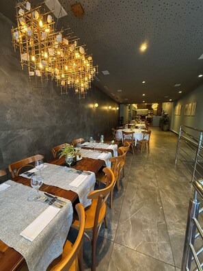 A restaurant with multiple tables, chairs, and a unique hanging light fixture. - Promenade Pancetti Belo Horizonte (Belo Horizonte)
