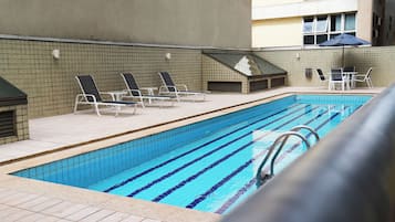 Una piscina al aire libre, sillones reclinables de piscina