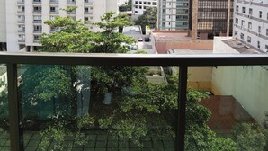 A high-rise building with multiple floors and balconies, viewed from a window with a metal railing. - Promenade Pancetti Belo Horizonte (Belo Horizonte)