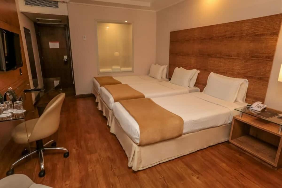 A hotel room with two beds, a desk with a chair, a telephone, and a small table.