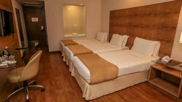 Una camera d'albergo con due letti, una scrivania con sedia, un telefono e un piccolo tavolino.