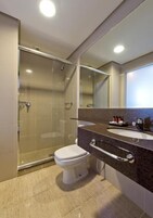 Un bagno moderno con doccia vetrata, un WC bianco e un piano di lavoro in granito con specchio.