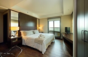 Una camera d'albergo con un letto grande, una TV, una scrivania e una finestra vista.