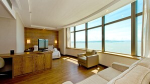 Une chambre d’hôtel moderne dotée d’un bureau en bois, d’un téléviseur à écran plat, d’un canapé confortable et d’une grande fenêtre donnant sur l’eau.