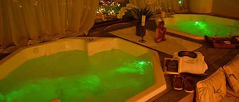 Un área de spa con dos jacuzzis, toallas y una botella de loción.