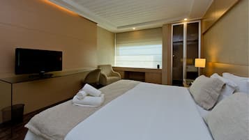 Quarto de hotel com cama, televisão, escrivaninha e cadeira.