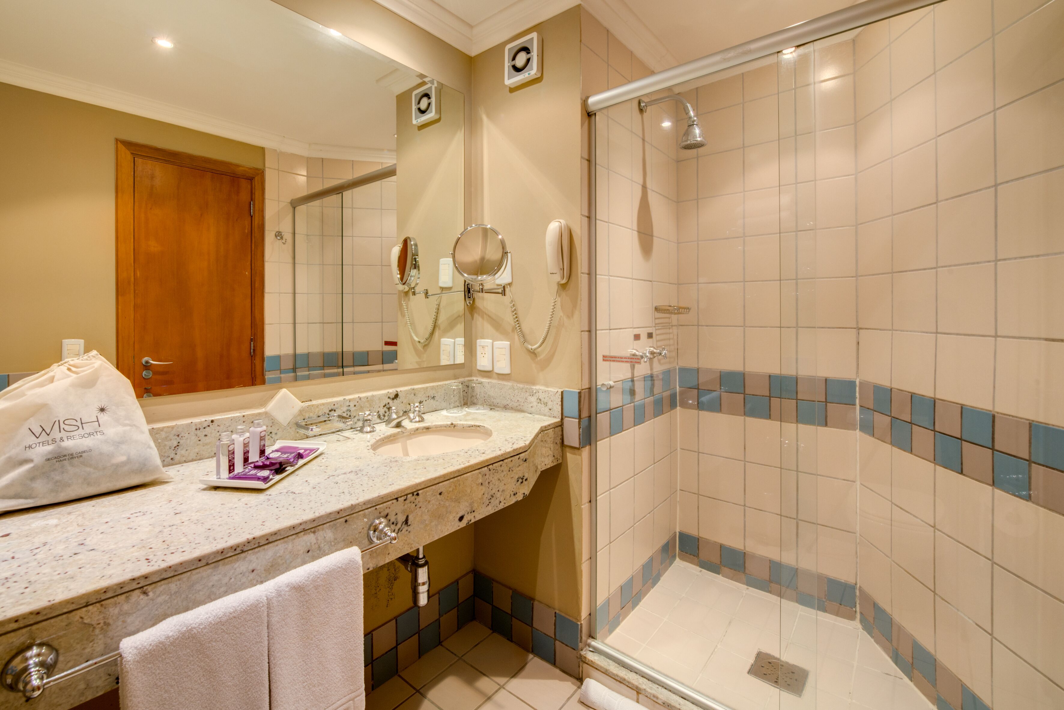 Een badkamer met een wastafel, spiegel en douche.