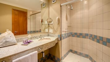 Een badkamer met een wastafel, spiegel en douche.