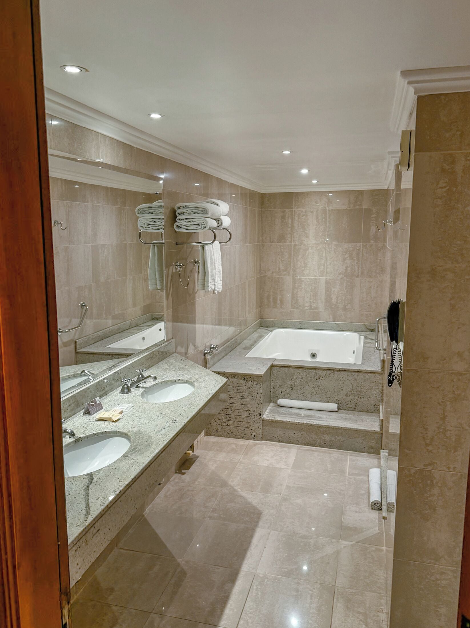 A spacious bathroom with two sinks, a large bathtub, and a separate shower area.
