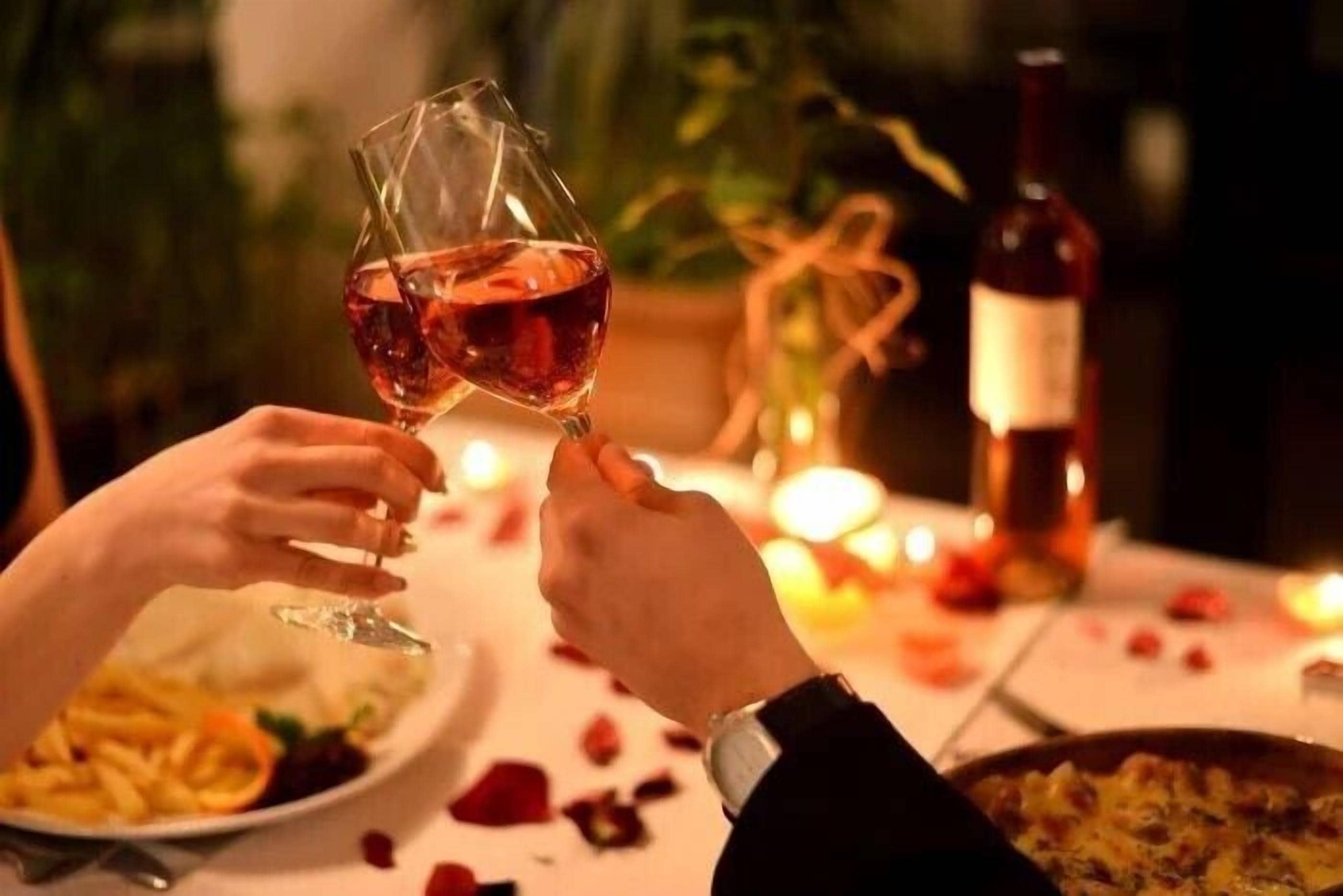 A dining table with a bottle of wine, a glass, and a plate of food.