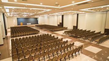 Un salón de conferencias con filas de sillas, un escenario y un atril.