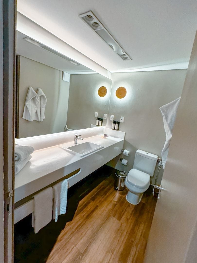 Une salle de bain moderne avec un grand miroir, deux vasques et des toilettes.