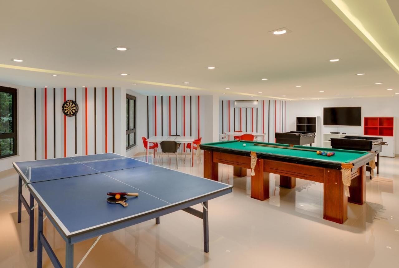 Un'area ricreativa interna moderna con tavolo da ping pong, tavolo da biliardo e tavolo da calcio.