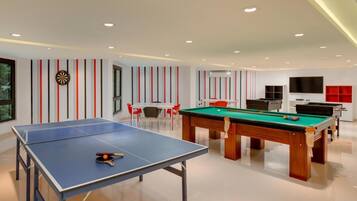 Un'area ricreativa interna moderna con tavolo da ping pong, tavolo da biliardo e tavolo da calcio.