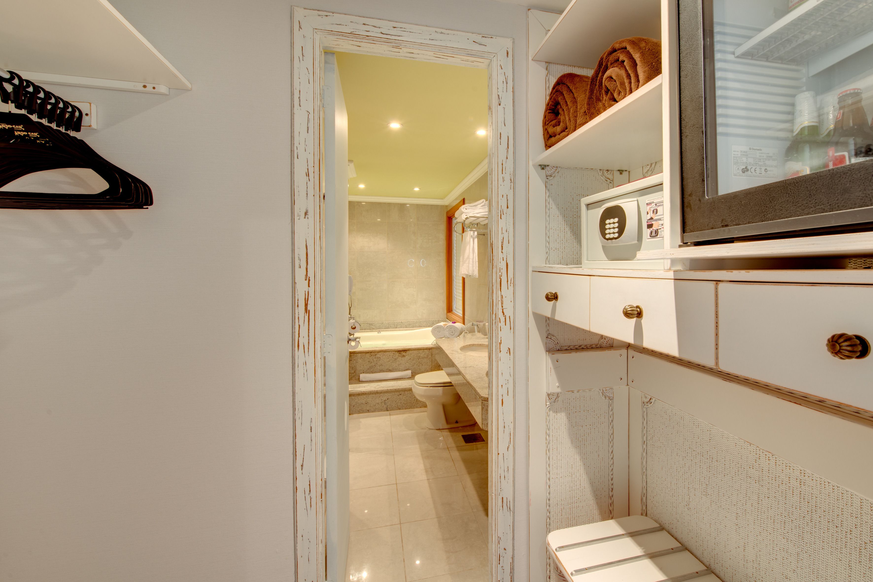 A bathroom with a bathtub, toilet, and a shower area. There is a towel rack with towels and a mirror above the sink.