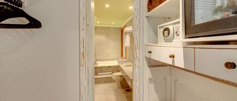 A bathroom with a bathtub, toilet, and a shower area. There is a towel rack with towels and a mirror above the sink.
