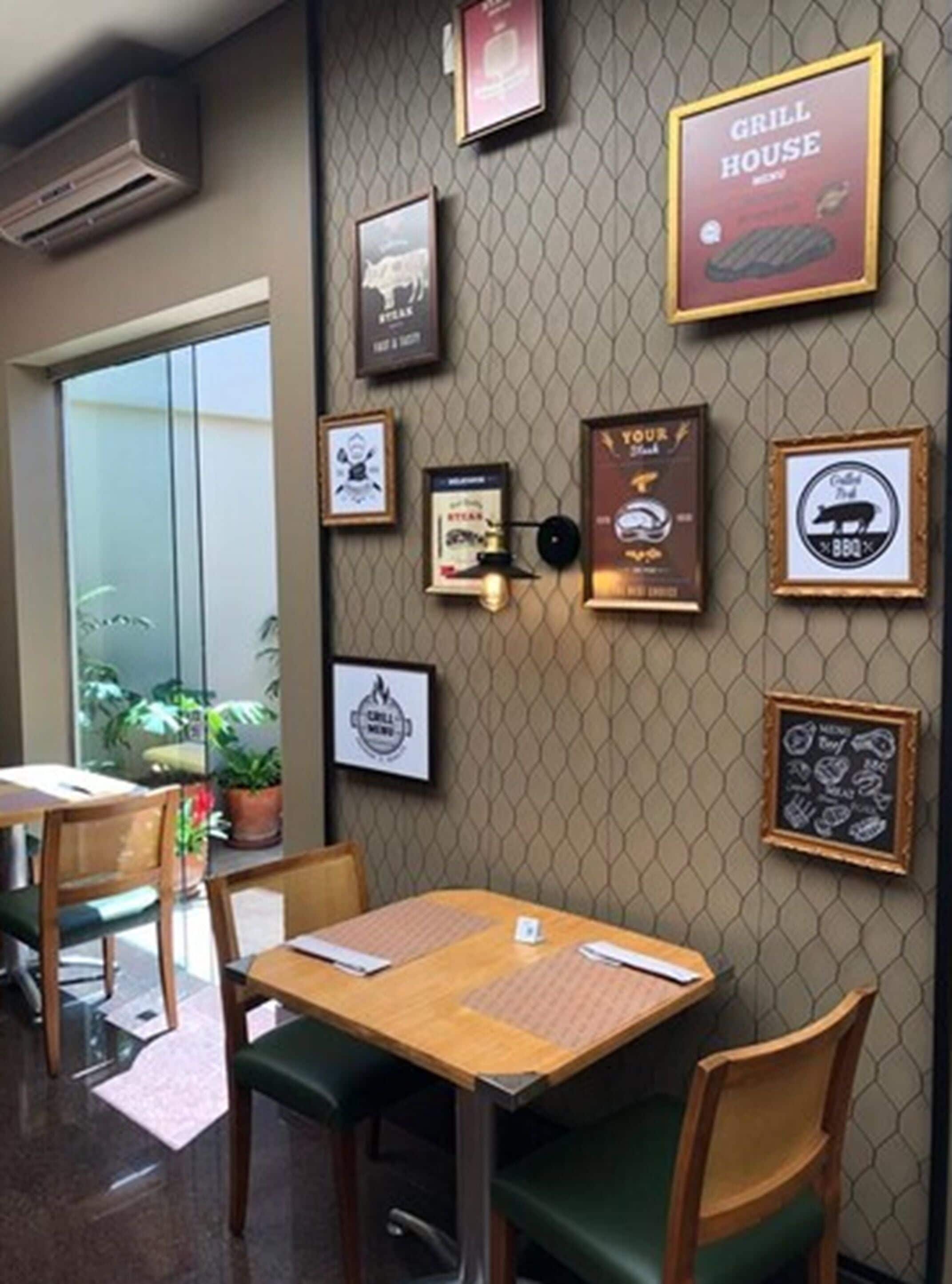 A restaurant interior with a wall decorated with framed pictures and a sign that reads "GRILL HOUSE."
