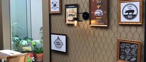 A restaurant interior with a wall decorated with framed pictures and a sign that reads "GRILL HOUSE."