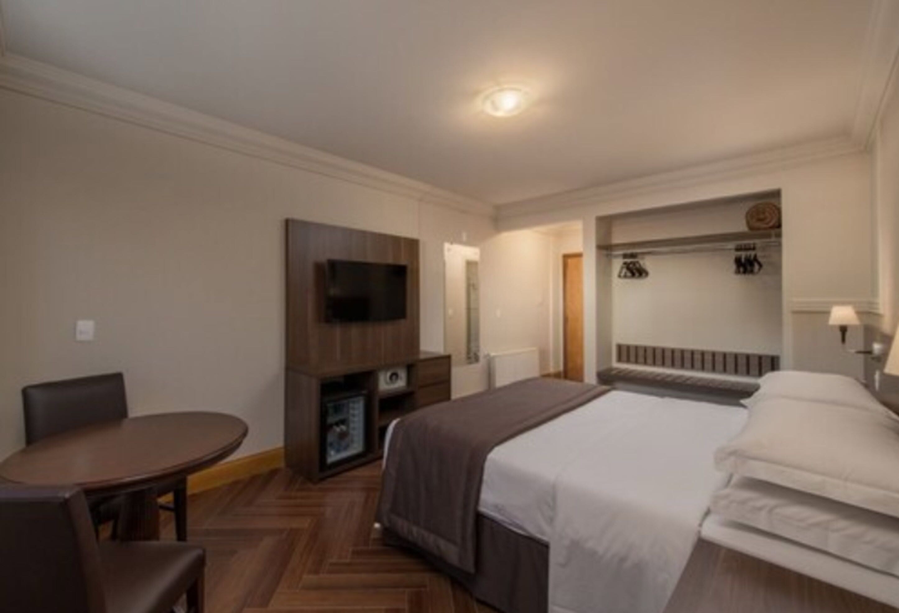 A hotel room with a bed, a TV, a desk, and a chair.