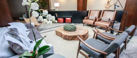En moderne hotellobby med læderarmstole, et træbord og en stor, hvid orchidé.