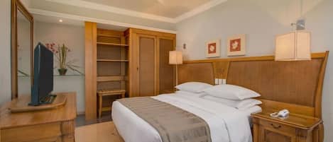 Una habitación de hotel con cama, mesita de noche, lámpara y armario.