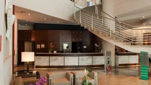 Un vestíbulo amplio con mostrador de recepción, zona de estar y una escalera que conecta varios pisos.