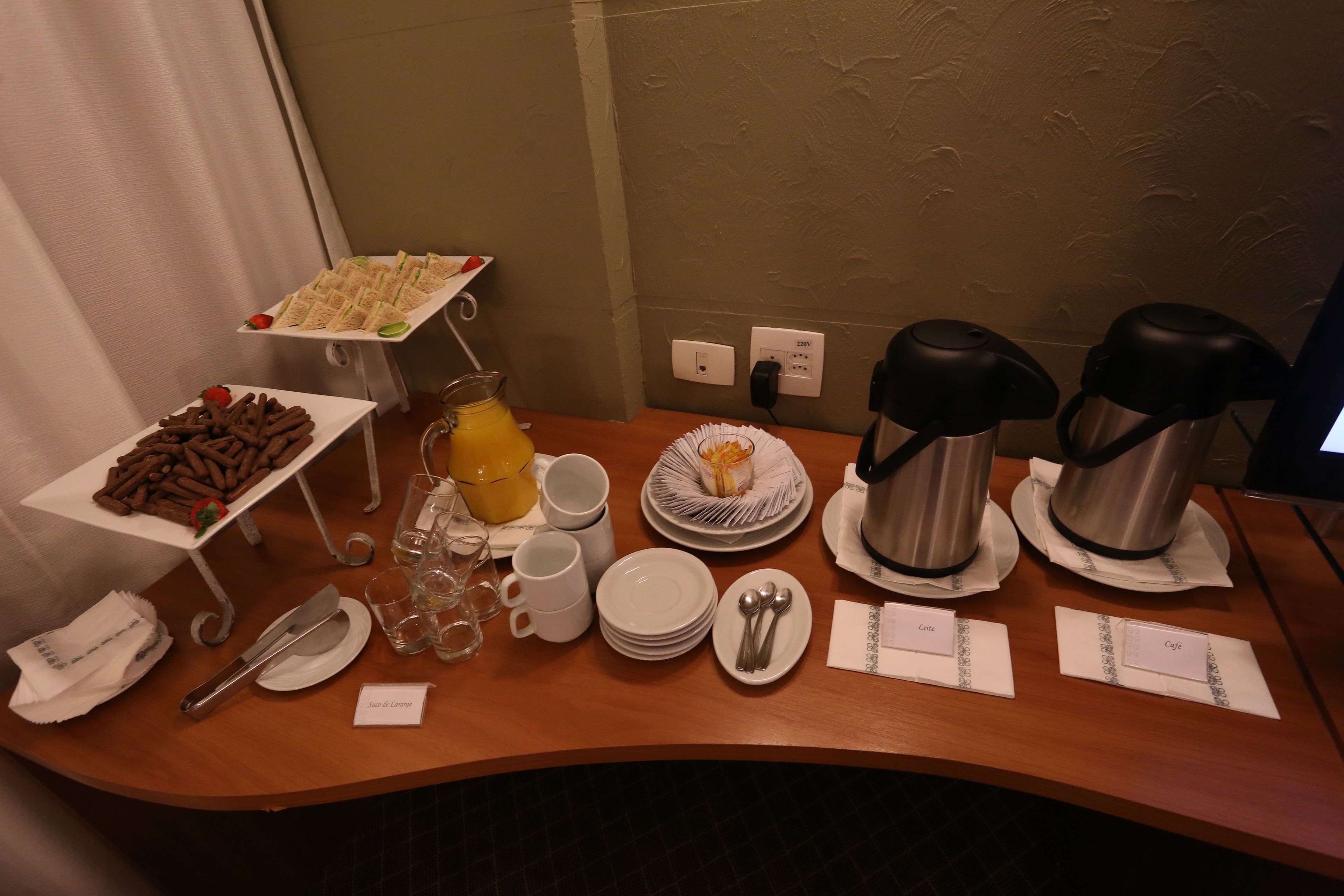 A breakfast buffet with various food items, coffee makers, and dining utensils on a wooden table.