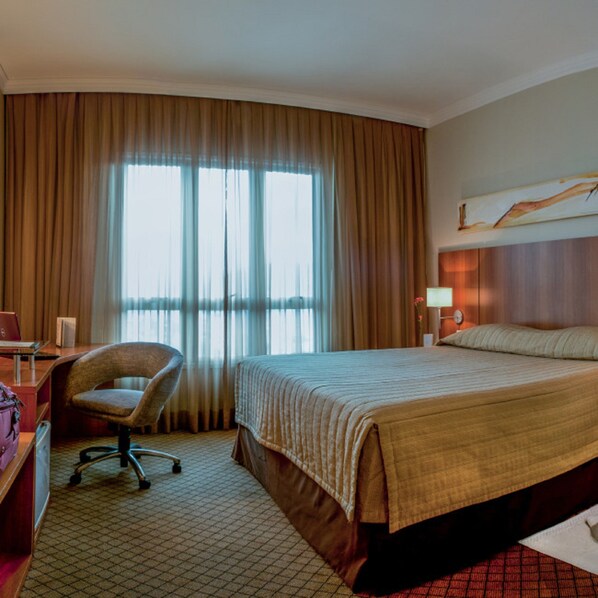 A hotel room with a bed, a desk, a chair, and a large window with curtains. - Bourbon Convention Hotel Joinville (Joinville)