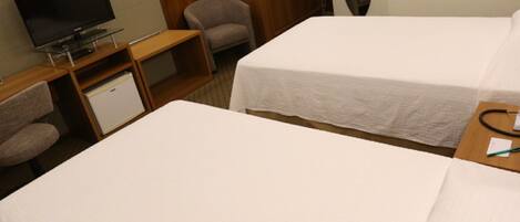 A hotel room with two beds, a TV, a desk, and a chair.