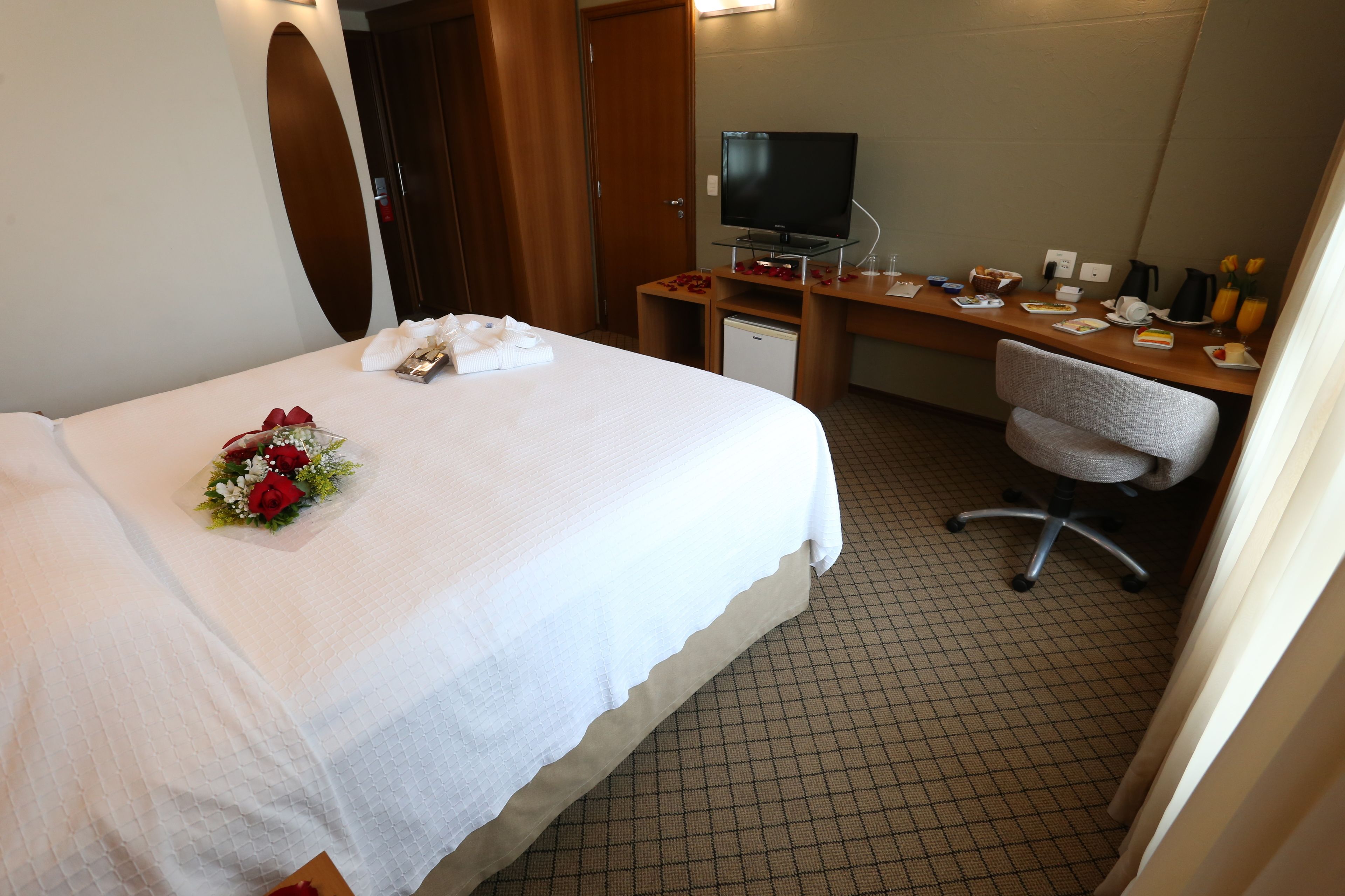 A hotel room with a bed, a desk, a television, and a chair.