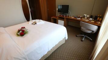A hotel room with a bed, a desk, a television, and a chair.