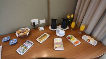 Um buffet de café da manhã com diversos alimentos, acompanhamentos e bebidas sobre uma mesa de madeira.