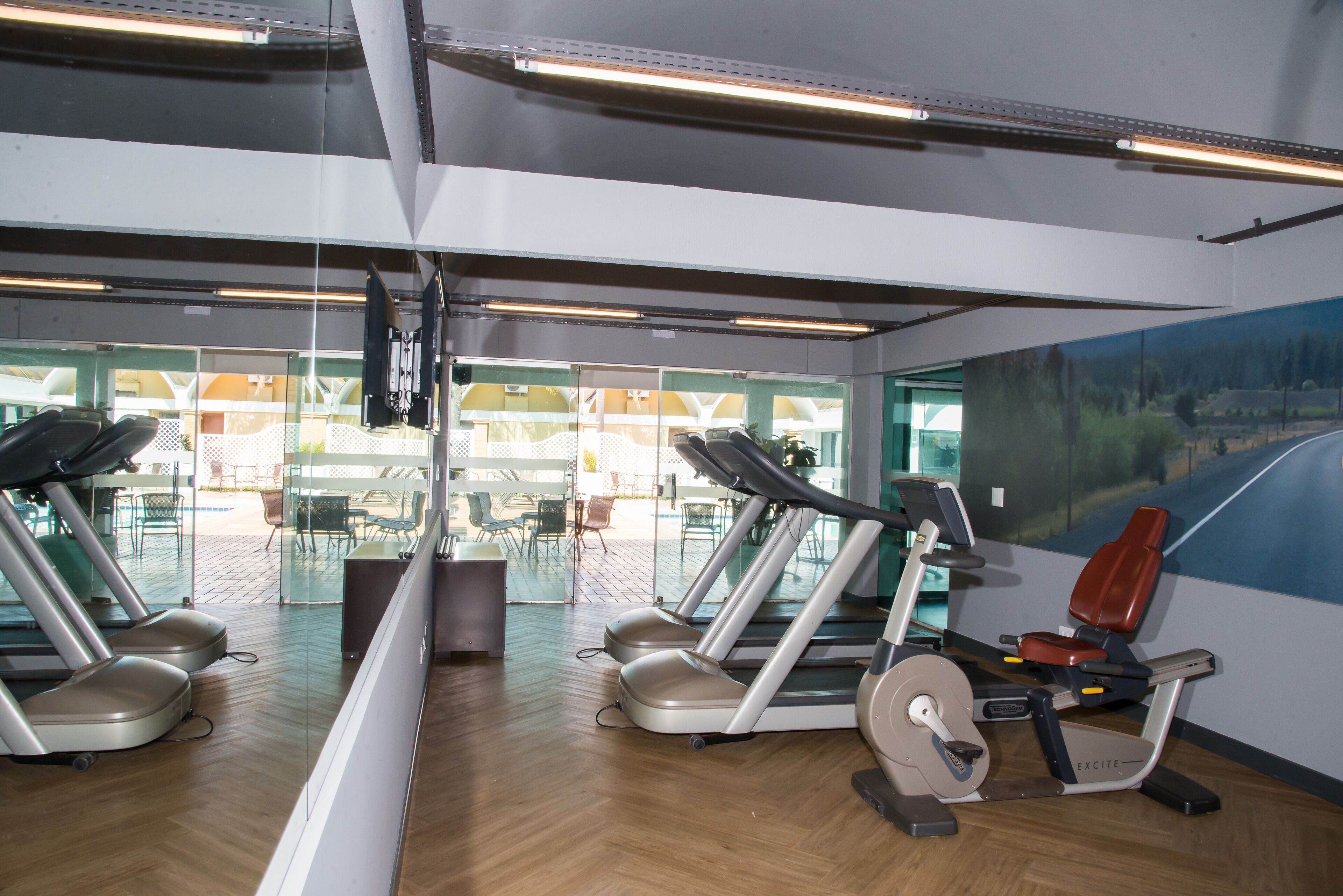 Een sportschool met loopbanden, een hometrainer en een roeiapparaat.