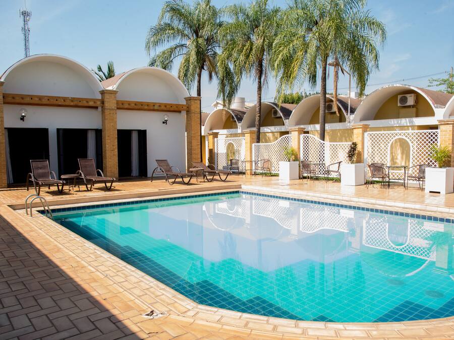 Una piscina con sillones de descanso y palmeras.