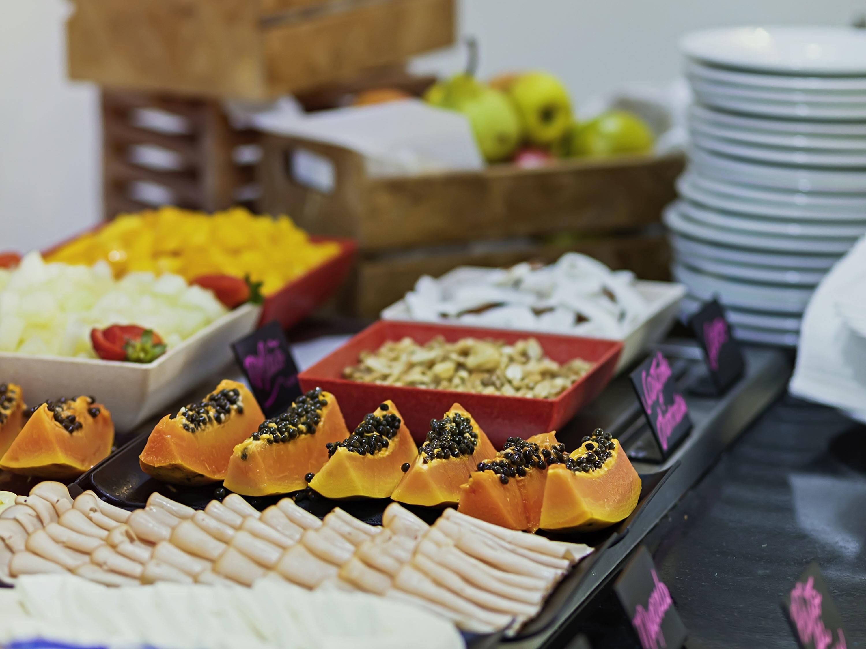 A buffet with various food items including fruits, nuts, and sliced meats.