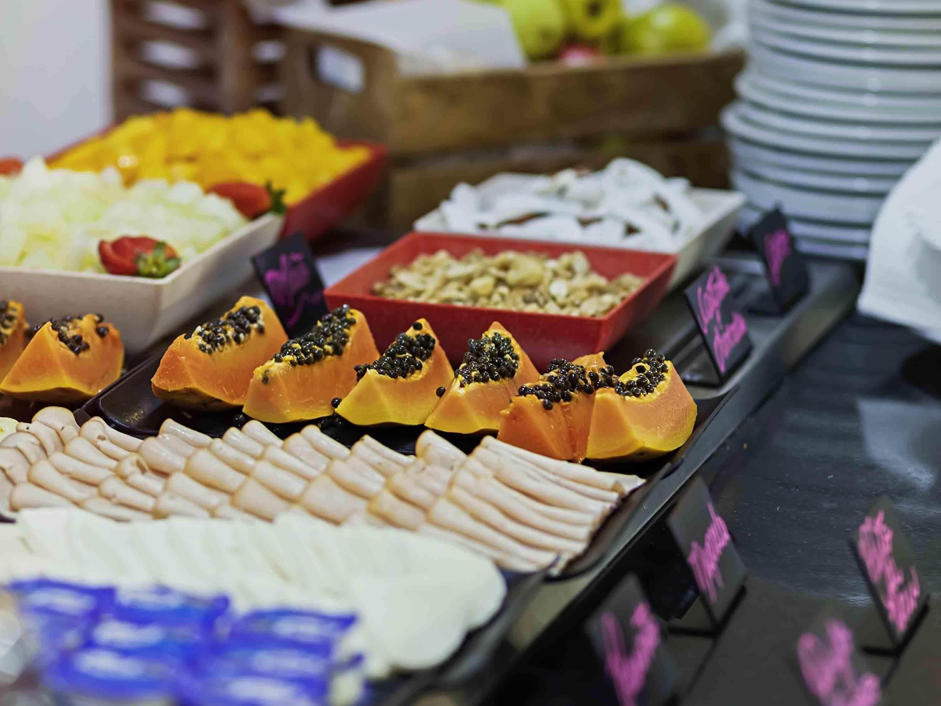 Ein Buffet mit verschiedenen Speisen, darunter Papaya, Käse und weitere Gerichte.