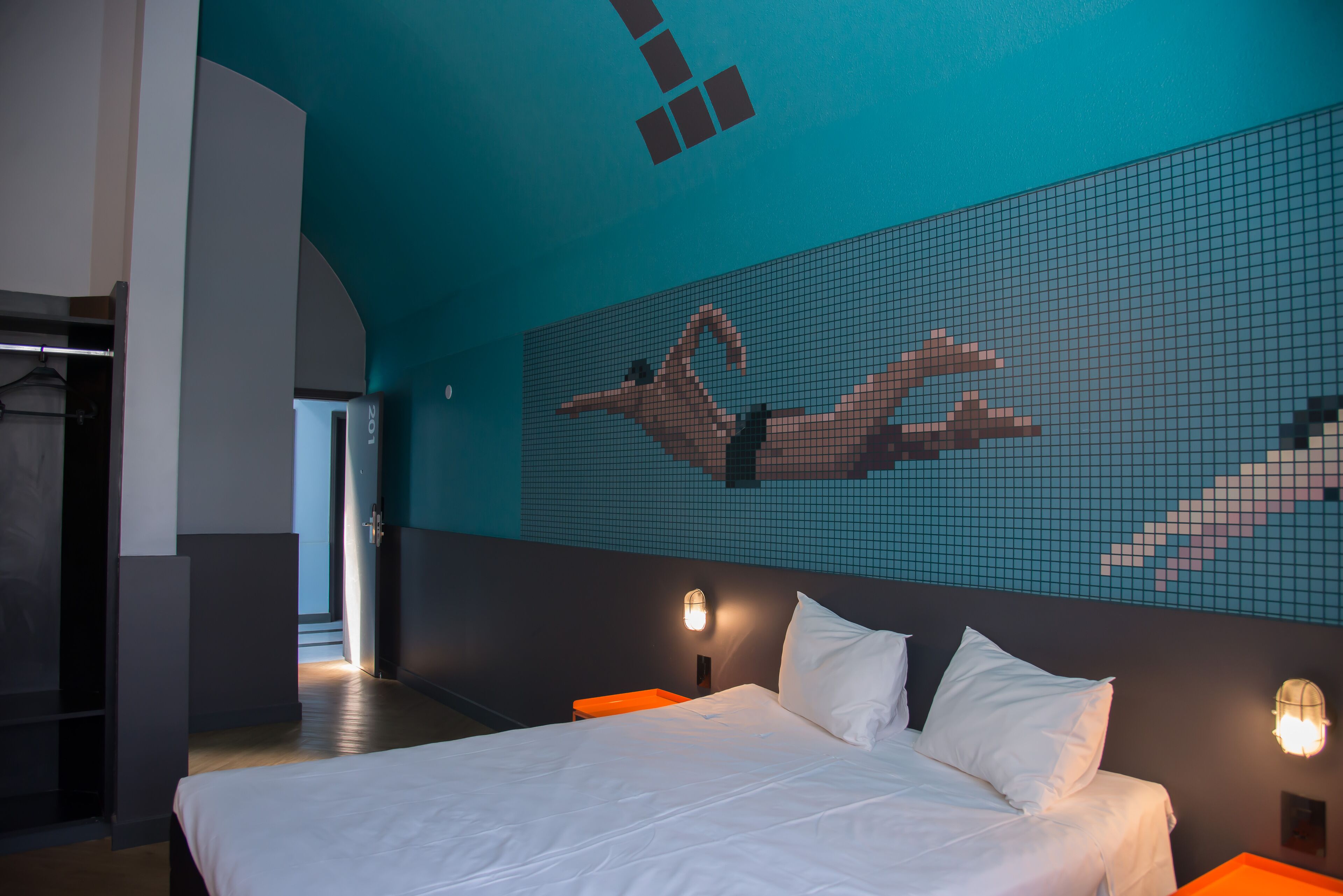 Een moderne hotelkamer met een groot bed, een muurschildering van een duiker en uitzicht op de gang.