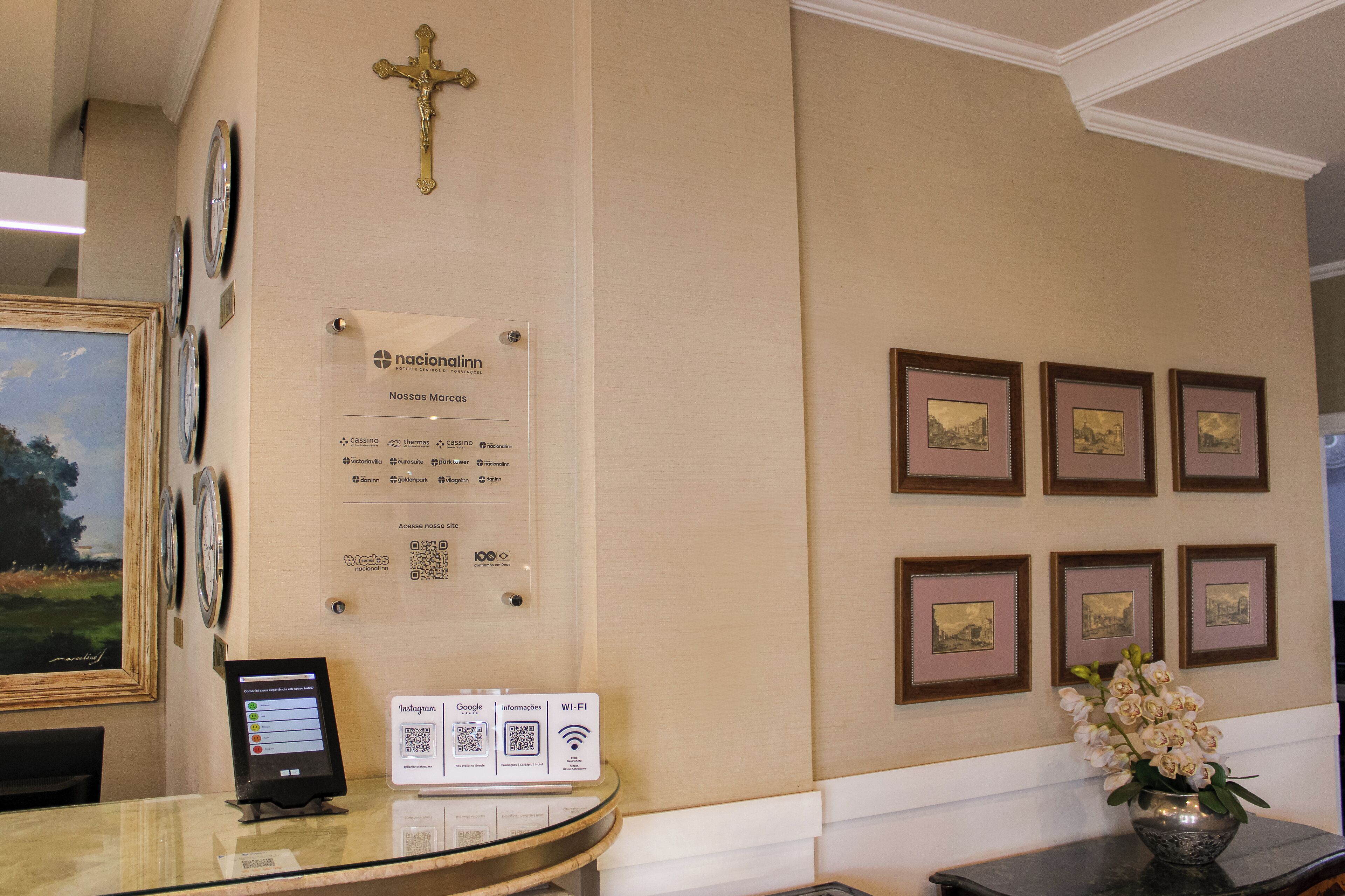 A reception area with a framed cross, a sign with a QR code, and framed pictures on the wall.
