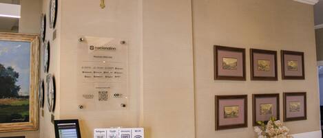 A reception area with a framed cross, a sign with a QR code, and framed pictures on the wall.