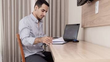A person sitting at a wooden table with a laptop and a notebook.