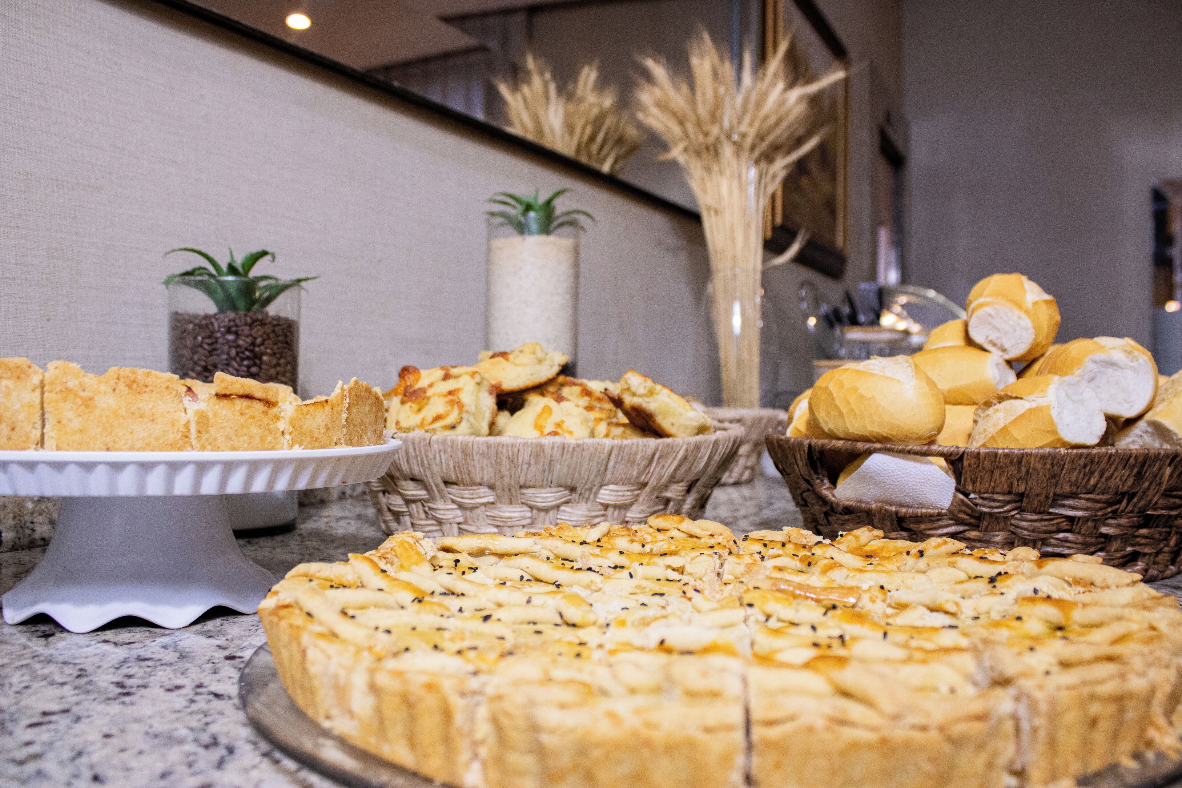 A buffet table with various baked goods, including bread and pastries, arranged on a marble countertop.